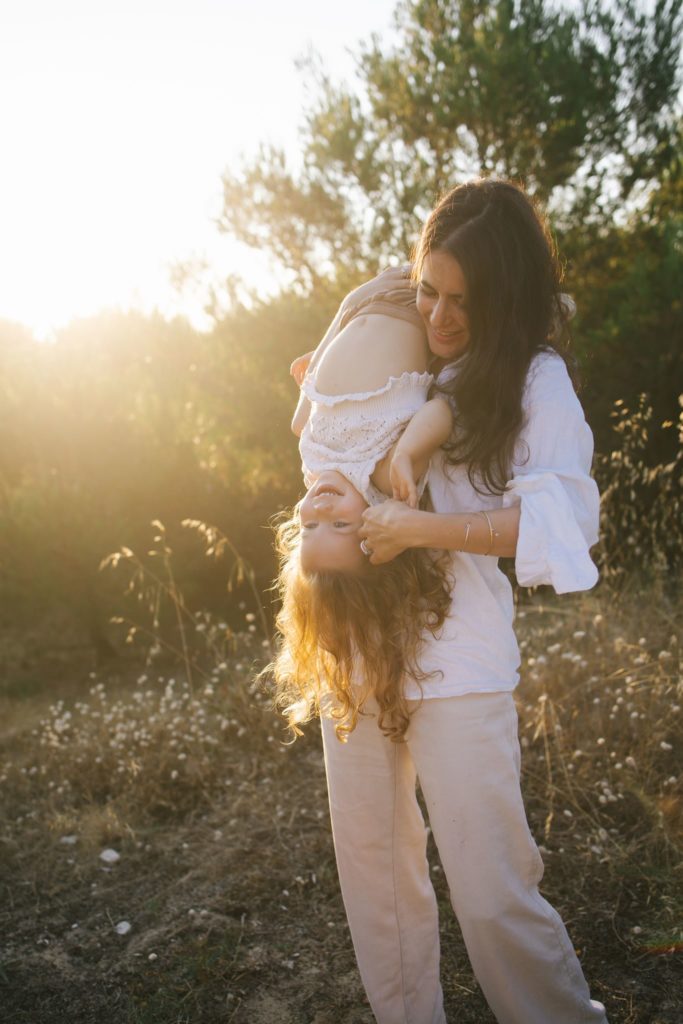 Photographe famille île de Ré : une maman porte sa fille dans les bras en pleine lumière